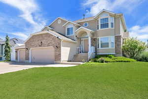 Traditional-style house with brick siding, concrete driveway, a front lawn, and stucco siding