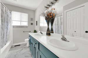 Full bathroom featuring double vanity, marble look tile flooring, and shower / tub combo
