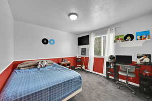 Bedroom featuring a textured ceiling, carpet floors, and an office area