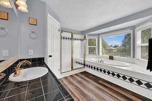 Bathroom featuring a bath, a shower stall, wood finished floors, and a textured ceiling