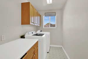 Washroom with cabinet space, washing machine and dryer, and light flooring