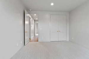 Unfurnished bedroom with recessed lighting, light carpet, and a closet