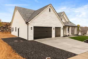 View of home's exterior featuring driveway, stucco siding, an attached garage, and stone siding
