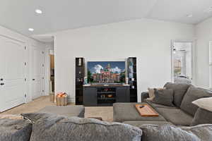 Carpeted living room with lofted ceiling and recessed lighting