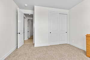 Unfurnished bedroom with light carpet and a closet