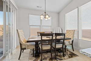 Dining room with light tile patterned floors, plenty of natural light, and a chandelier
