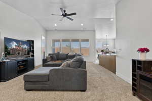 Living room with carpet flooring, a ceiling fan, lofted ceiling, recessed lighting, and a textured ceiling