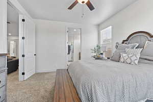 Bedroom featuring carpet floors, ceiling fan, and ensuite bath