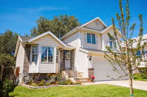 View of front of house with an attached garage, concrete driveway, and a shingled roof