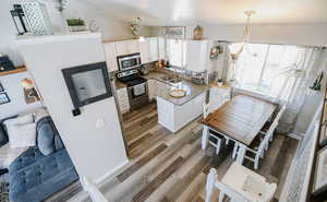 Kitchen featuring white cabinets, appliances with stainless steel finishes, decorative light fixtures, and a peninsula