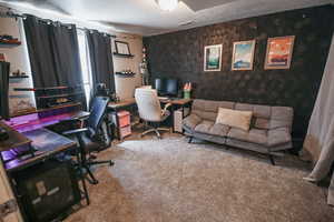 Carpeted office space featuring a textured ceiling, wallpapered walls, and an accent wall