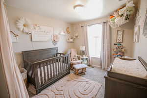 Carpeted bedroom featuring a crib and baseboards