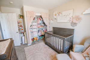 Bedroom with light carpet, a closet, and a nursery area