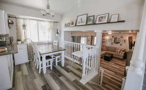 Dining space with dark wood-style floors, vaulted ceiling, and a chandelier