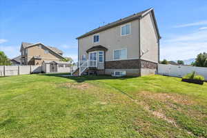 Back of house featuring a storage unit, stucco siding, a fenced backyard, and a gate