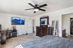 Bedroom featuring an office area, carpet floors, ensuite bath, and ceiling fan