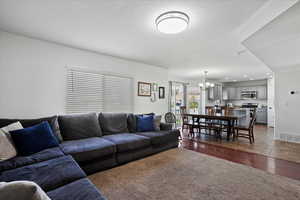 Living room with dark wood-style floors, a chandelier, a textured ceiling, and recessed lighting