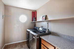Laundry room with washing machine and clothes dryer, cabinet space, and a textured ceiling