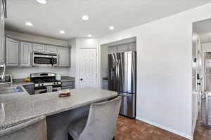 Kitchen featuring gray cabinetry, stainless steel appliances, a kitchen breakfast bar, a peninsula, and recessed lighting