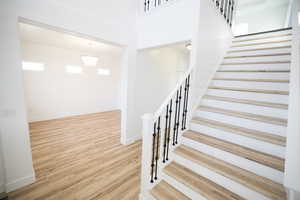 Stairs featuring wood finished floors, a towering ceiling, and a chandelier