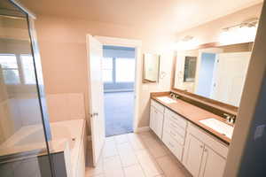 Full bathroom with double vanity, a garden tub, and tile patterned flooring