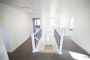 Corridor with an upstairs landing, carpet flooring, recessed lighting, and a chandelier