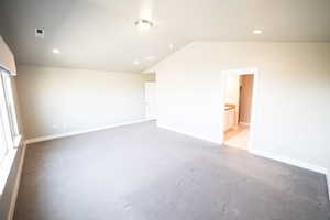 Unfurnished bedroom with light carpet, lofted ceiling, recessed lighting, and connected bathroom