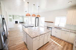 Kitchen featuring stainless steel fridge, decorative backsplash, a center island, light wood finished floors, and a fireplace