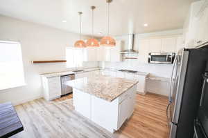 Kitchen with backsplash, appliances with stainless steel finishes, a center island, white cabinets, and recessed lighting