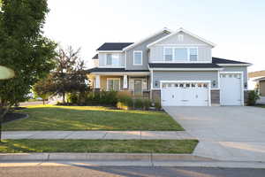 Craftsman-style house featuring concrete driveway, a front yard, stone siding, and an attached garage