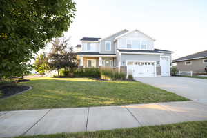 Craftsman-style house featuring an attached garage, driveway, a front lawn, and stone siding