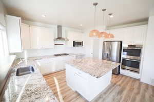 Kitchen with tasteful backsplash, appliances with stainless steel finishes, a center island, light stone counters, and recessed lighting