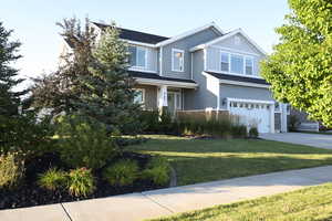 Craftsman inspired home featuring an attached garage, concrete driveway, a front yard, and a shingled roof