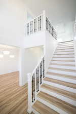 Staircase with wood finished floors, a high ceiling, and recessed lighting