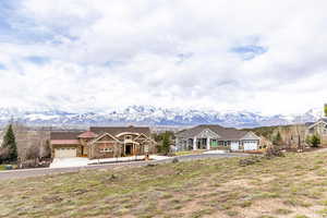 View of front of property featuring a mountain view, stone siding, driveway, and a garage