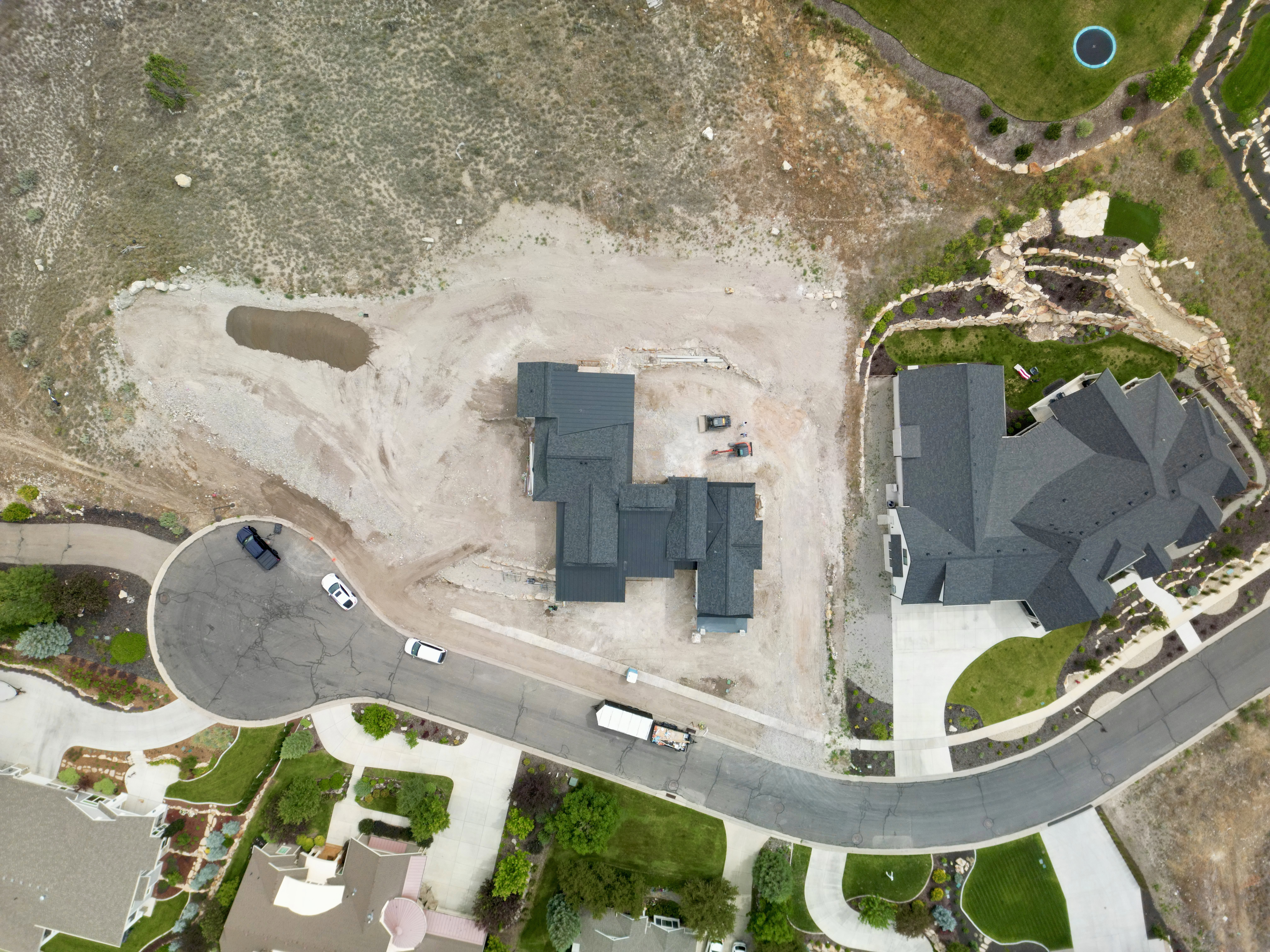 Newly constructed residence featuring a multi-gabled roofline, light-colored siding, and a paved driveway