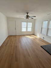 Unfurnished living room with light wood finished floors, a textured ceiling, and ceiling fan