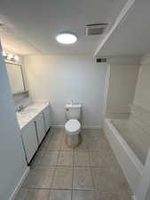 Bathroom featuring a textured ceiling, light tile patterned floors, vanity, and shower / bathtub combination