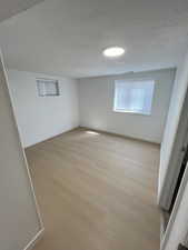 Unfurnished room featuring light wood-style floors and a textured ceiling