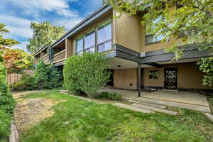 Rear view of house with a patio area, brick siding, and a balcony