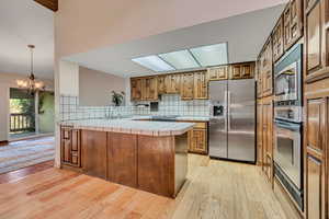 Kitchen with tile counters, a peninsula, and stainless steel appliances