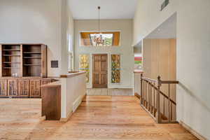 Entrance foyer featuring a high ceiling, light wood finished floors, and a chandelier