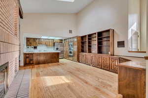 Kitchen with a peninsula, a towering ceiling, light wood-style flooring, appliances with stainless steel finishes, and wood cabinets