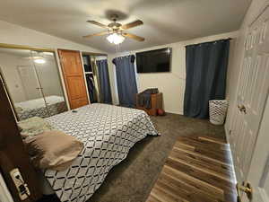 Bedroom featuring multiple closets, a ceiling fan, dark wood-style floors, and vaulted ceiling