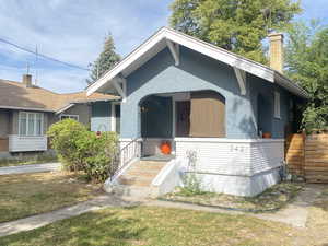 View of front facade featuring a chimney, covered porch, and a front yard