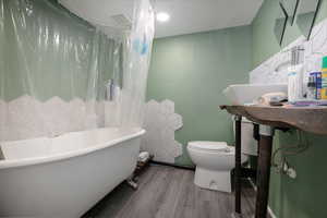 Full bathroom with wood finished floors and a combined bath / shower with freestanding tub