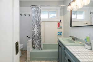 Bathroom with vanity, shower / bath combo with shower curtain, and tile patterned floors