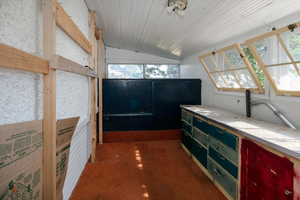 Bar area featuring lofted ceiling, green cabinets, dark carpet, and light countertops