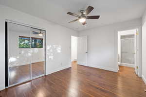 Unfurnished bedroom featuring dark wood-style flooring, a closet, a ceiling fan, and ensuite bath