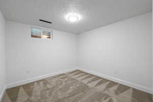 Spare room featuring carpet floors and a textured ceiling